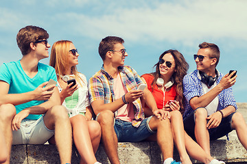 Image showing group of smiling friends with smartphones outdoors