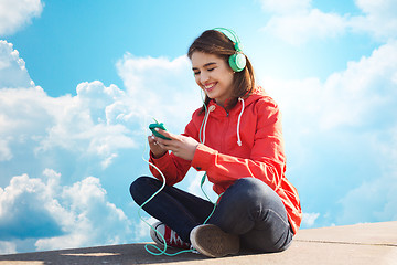 Image showing happy young woman with smartphone and headphones