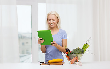 Image showing smiling young woman with tablet pc cooking at home