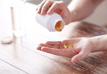 Image showing close up of man pouring fish oil capsules to hand