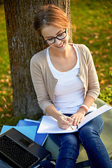 Image showing happy student girl writing to notebook at campus