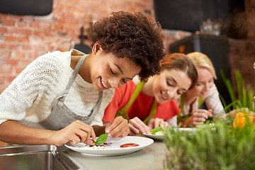 Image showing happy women cooking and decorating dishes