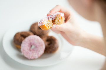 Image showing close up of hand holding bitten glazed donut