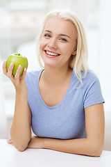 Image showing happy woman eating green apple at home