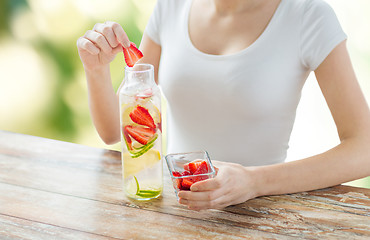 Image showing close up of woman with fruit water in glass bottle