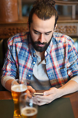 Image showing man with smartphone drinking beer at bar