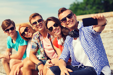 Image showing group of smiling friends with smartphone outdoors