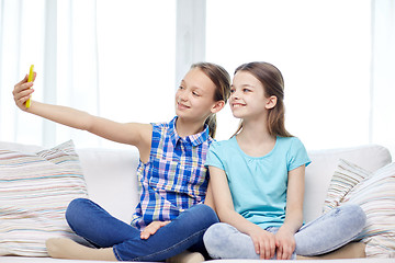 Image showing happy girls with smartphone taking selfie at home