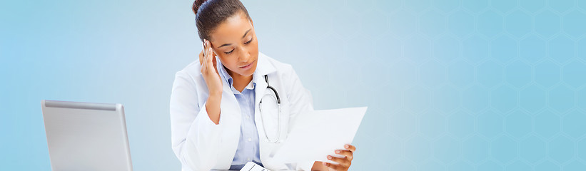 Image showing female doctor with laptop pc looking at paper