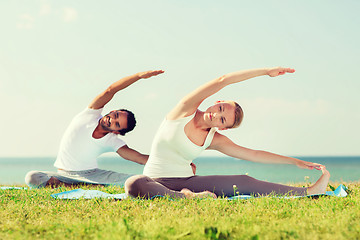 Image showing smiling couple making yoga exercises outdoors