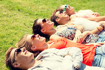 Image showing group of smiling friends lying on grass outdoors