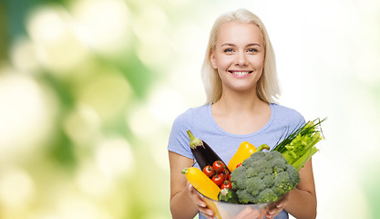 Image showing smiling young woman with vegetables over green