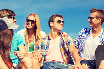 Image showing group of smiling friends sitting on city street