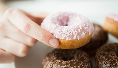 Image showing close up of hand holding glazed donut