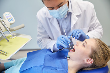 Image showing male dentist in mask checking female patient teeth