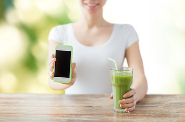 Image showing close up of woman with smartphone and green juice