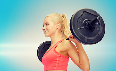 Image showing smiling sporty woman exercising with barbell