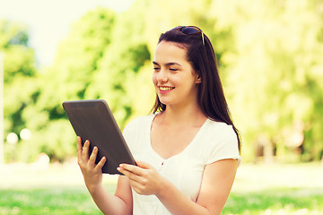 Image showing smiling young girl with tablet pc sitting on grass