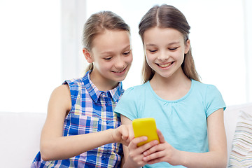 Image showing happy girls with smartphone sitting on sofa