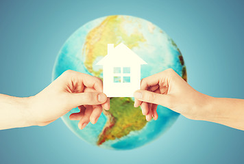 Image showing couple hands holding green house over earth globe