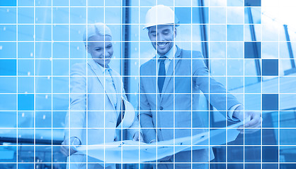 Image showing smiling business people in helmets with blueprint