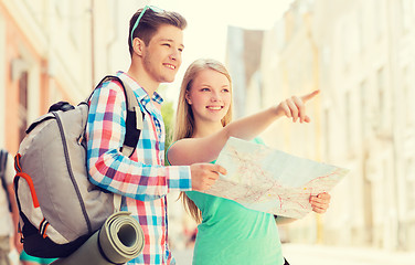 Image showing smiling couple with map and backpack in city