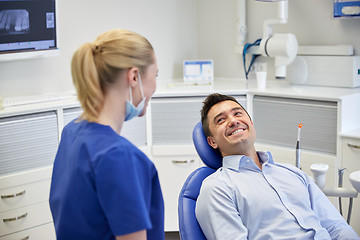 Image showing happy female dentist with man patient at clinic