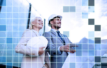 Image showing smiling business people in helmets with blueprint