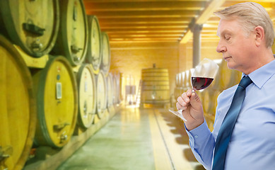 Image showing senior man smelling red wine in cellar
