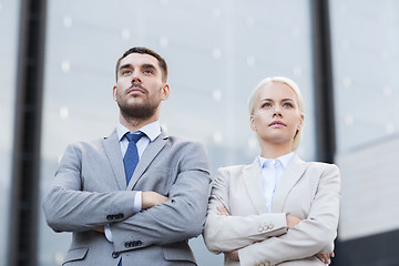 Image showing serious businessmen standing over office building