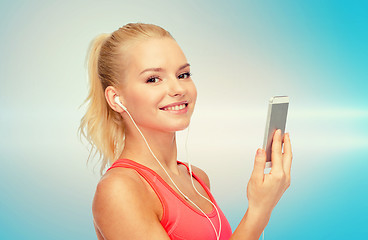 Image showing smiling sporty woman with smartphone and earphones