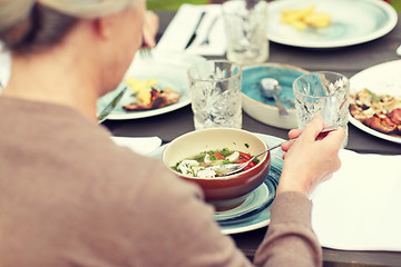 Image showing close up of woman eating soup in summer garden