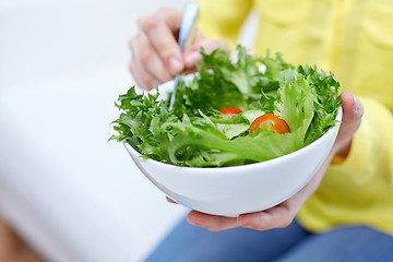 Image showing close up of young woman eating salad at home