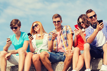 Image showing group of smiling friends with smartphones outdoors