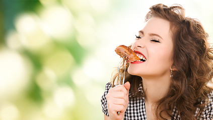 Image showing hungry young woman eating meat on fork over green