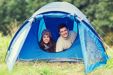 Image showing smiling couple of tourists looking out from tent