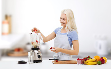 Image showing smiling woman with blender preparing shake