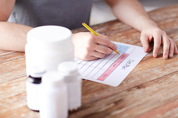 Image showing close up of man with protein jars and diet plan