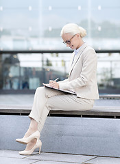 Image showing young smiling businesswoman with notepad outdoors