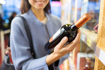 Image showing happy woman choosing and buying wine in market