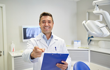 Image showing happy dentist pointing to you at dental clinic