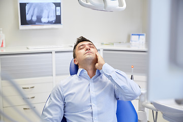 Image showing man having toothache and sitting on dental chair