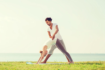 Image showing smiling couple making yoga exercises outdoors