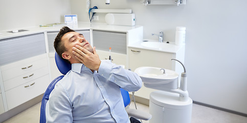 Image showing man having toothache and sitting on dental chair