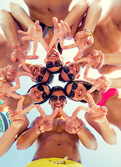 Image showing smiling friends in circle on summer beach