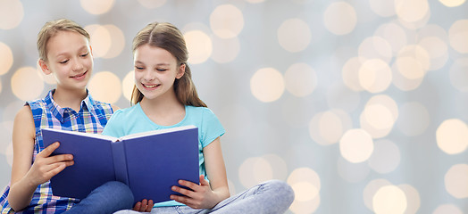 Image showing happy girls reading book over lights background