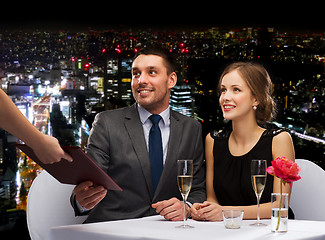 Image showing waiter giving menu to happy couple at restaurant