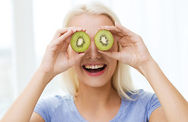 Image showing happy woman having fun covering eyes with kiwi