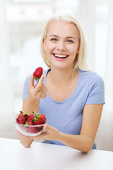 Image showing happy woman eating strawberry at home