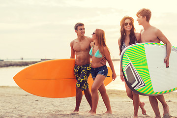 Image showing smiling friends in sunglasses with surfs on beach